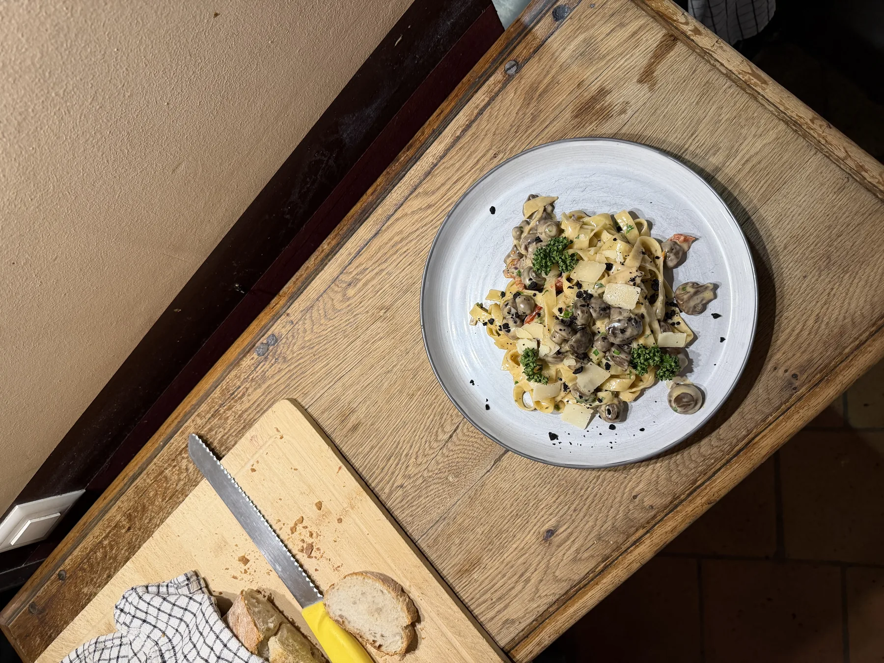 Tagliatelles aux champignons, copeaux de parmesan et persil, servies sur une table en bois de l'Étoile Blanche